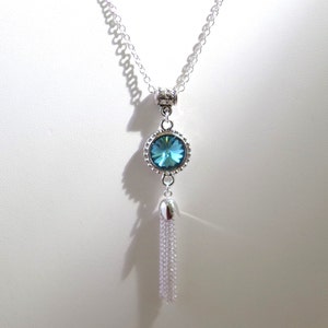 May include: A silver chain necklace with a blue crystal pendant and a silver tassel.