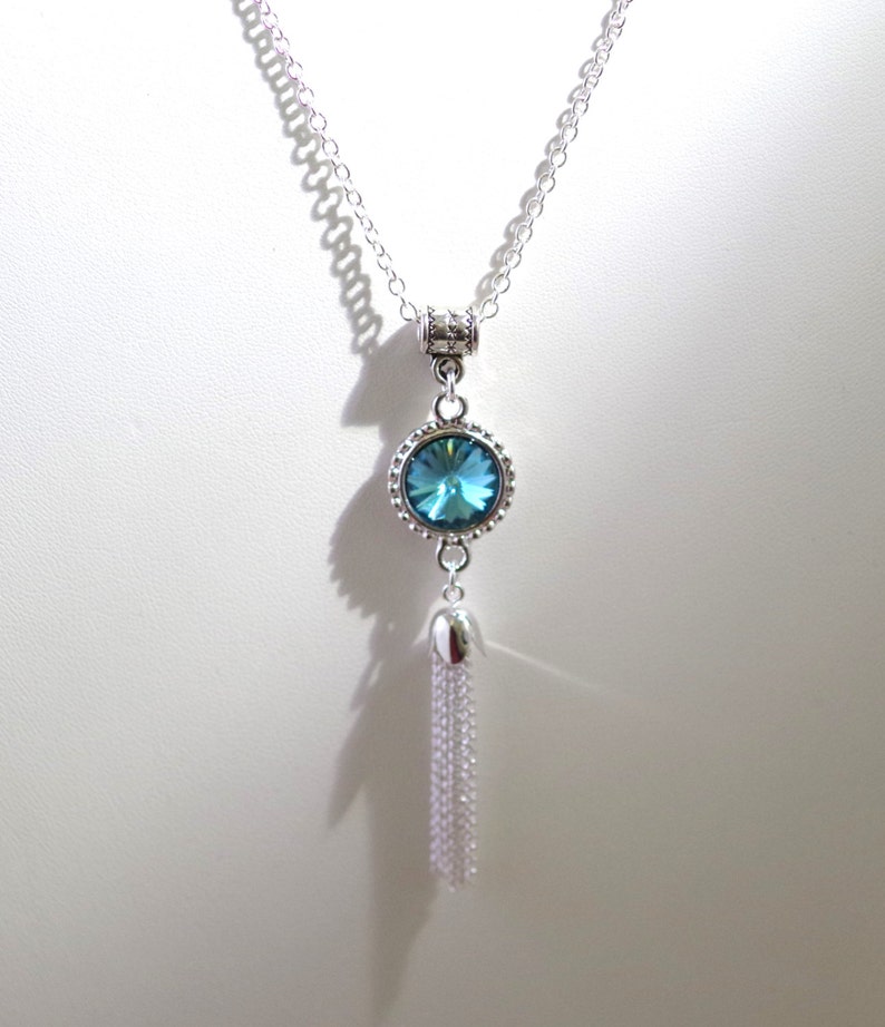 May include: A silver chain necklace with a blue crystal pendant and a silver tassel.