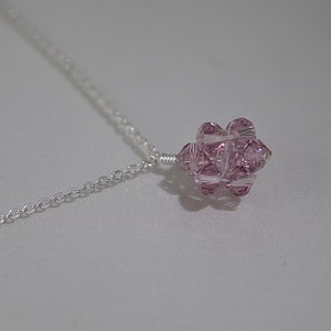 Puede incluir: Un delicado collar de cadena de plata con un colgante de cristal rosa. El colgante es un racimo de cristales facetados, creando un efecto brillante.
