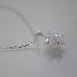 Puede incluir: Un collar de cadena de plata con un colgante de cristal transparente. El colgante est&aacute; hecho de muchos cristales peque&ntilde;os que se agrupan para formar una bola.
