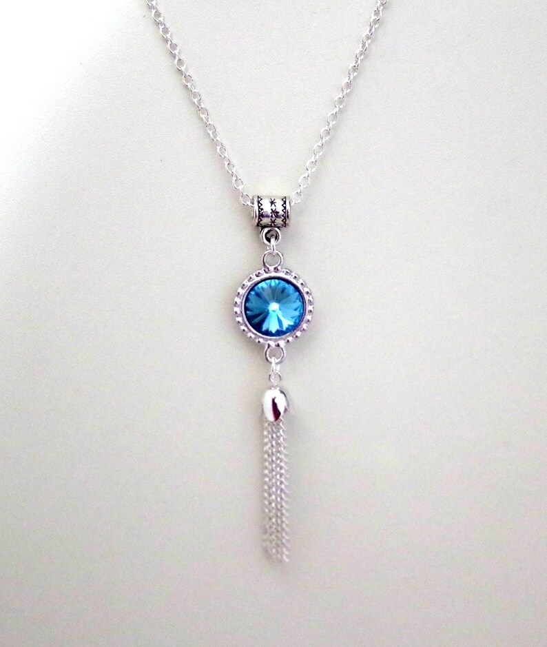 May include: A silver chain necklace with a blue crystal pendant and a silver tassel.