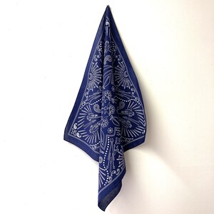Puede incluir: Un pa&ntilde;uelo azul marino con un dise&ntilde;o paisley blanco. El pa&ntilde;uelo presenta una variedad de patrones blancos, incluyendo estrellas, remolinos y formas geom&eacute;tricas.
