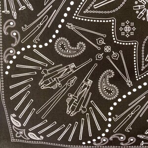 Puede incluir: Bandana de color negro y blanco con estampado paisley y un dise&ntilde;o de varias herramientas, incluyendo alicates, destornilladores y llaves.