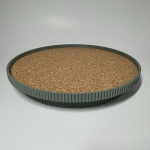 Könnte beinhalten: Ein rundes, grünes Tablett mit Korkauskleidung und einem strukturierten Rand.