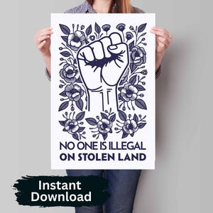 May include: A black and white illustration of a raised fist surrounded by stylised flowers. The text "NO ONE IS ILLEGAL ON STOLEN LAND" is below the fist.