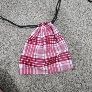 May include: A red and white plaid drawstring bag with black drawstrings.