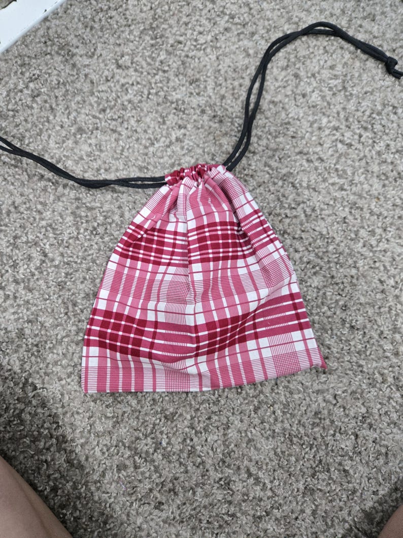 May include: A red and white plaid drawstring bag with black drawstrings.
