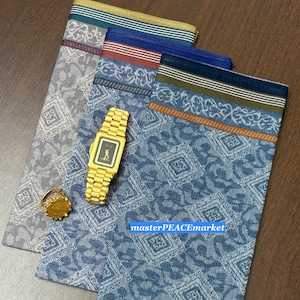 May include: Three patterned handkerchiefs in blue, gray, and white with decorative borders. A gold watch and a gold ring are placed on top of the handkerchiefs. The text "masterPEACEmarket" is visible on the blue handkerchief.