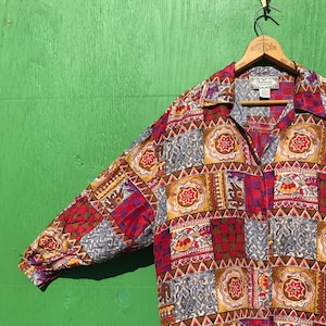 May include: A long-sleeved button-down shirt with a patchwork design. The shirt features a variety of colors and patterns, including red, brown, yellow, and blue. The shirt is made of a silky fabric and has a relaxed fit.