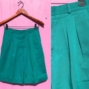 May include: Teal green high-waisted shorts with pleats and a button closure.