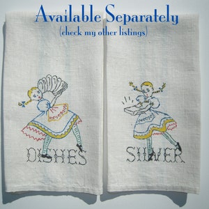 May include: Two off-white linen kitchen towels featuring embroidered illustrations of a girl in a dress. The left towel shows the girl holding dishes with the text DISHES below. The right towel shows the girl holding silver with the text SILVER below.