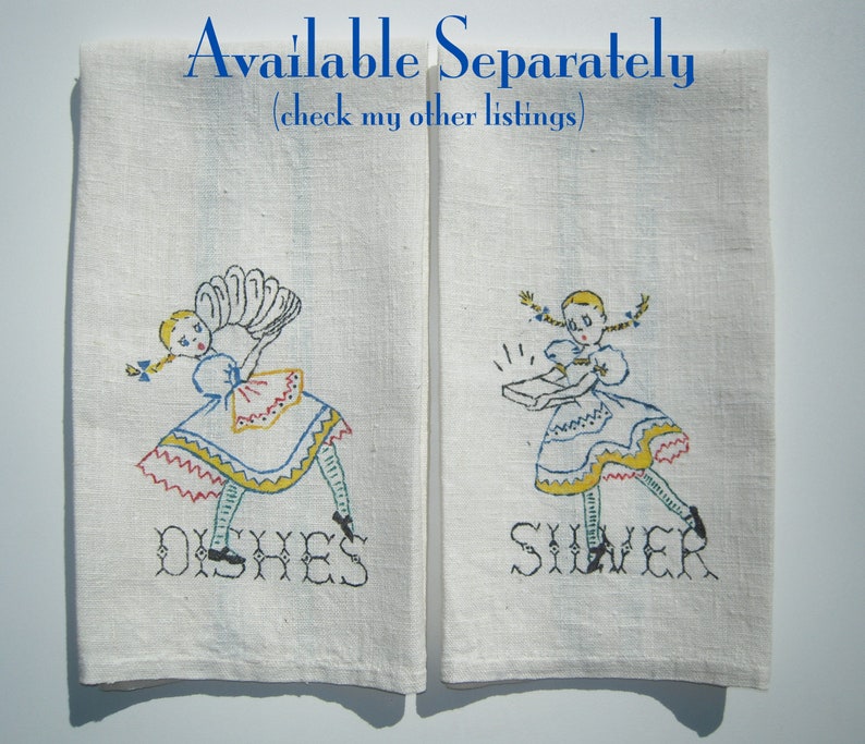 May include: Two off-white linen kitchen towels featuring embroidered illustrations of a girl in a dress. The left towel shows the girl holding dishes with the text DISHES below. The right towel shows the girl holding silver with the text SILVER below.