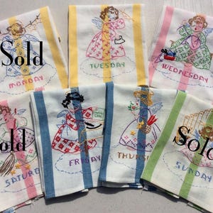 May include: A set of vintage embroidered kitchen towels, each marked with a day of the week. The towels have striped borders in different colours and feature angel designs. Some towels have the word "Sold" printed on them.