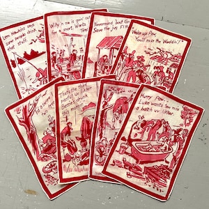 May include: A set of seven rectangular white fabric napkins with red borders, each featuring a unique red ink illustration of hillbilly characters and humorous text captions including phrases like 'Wake up Paw' and 'That's the third panful'.