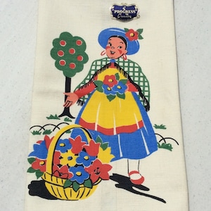 May include: A vintage kitchen towel with a colorful illustration of a girl holding a basket of flowers. The girl is wearing a blue dress, a red and white checkered shawl, and a blue hat. The towel has a "Progress Creation" tag.