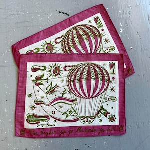 May include: Two vintage handkerchiefs with a hot air balloon design in pink and green on a white background. The handkerchiefs have a pink border and feature the text "The higher you go the harder you fall."