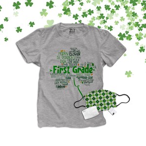 以下が含まれることがあります： 緑と白の模様で「First Grade」と書かれた灰色のTシャツ。クローバーと聖パトリックの日に関連する他の言葉も書かれています。緑と白の模様のフェイスマスクと白いフィルターが付属しています。
