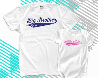 May include: White t-shirt with the text "Big Brother Lucas" in a blue baseball font. White bodysuit with the text "Little Sister Marie" in a pink baseball font.