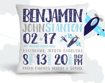May include: White pillow with blue and gray text that reads "BENJAMIN JOHNSTANTON 02-17 TWO THOUSAND TWENTY-THREE KITTYHAWK. NORTH CAROLINA 8 POUNDS 13 OUNCES 20 INCHES 11:02 PM PROUD PARENTS ROBERT & SOPHIE". Two blue airplanes with white stars are on the pillow.