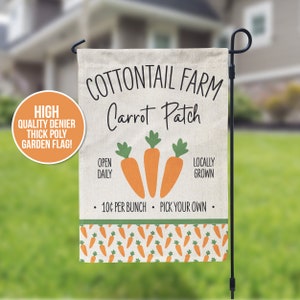 May include: A white garden flag with the text "COTTONTAIL FARM Carrot Patch" in black. The flag also has a green and orange carrot design and the text "OPEN DAILY", "LOCALLY GROWN", "10¢ PER BUNCH", and "PICK YOUR OWN".