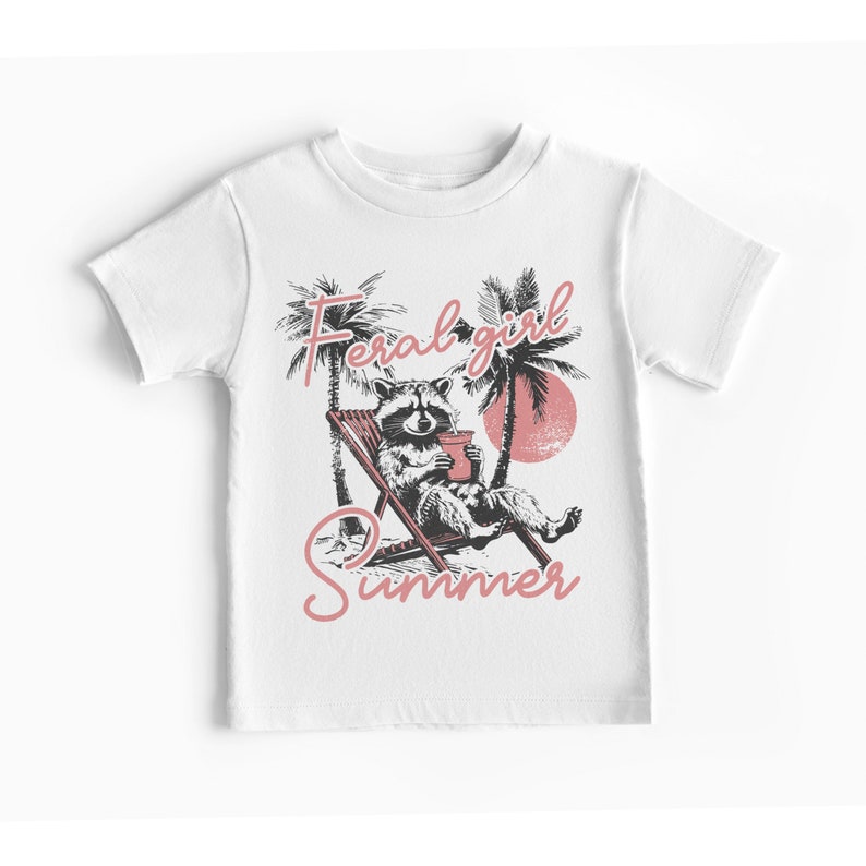 May include: White t-shirt with a graphic of a raccoon sitting in a beach chair with a drink, palm trees, and the text "Feral girl summer" in pink.