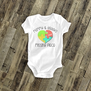 May include: White baby onesie with the text "mommy & daddy's missing piece" in black. A heart-shaped puzzle piece design is in the center with the names "Chase" and "Hudson" in the puzzle pieces.