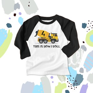 May include: A white and black baseball tee shirt with a yellow cement mixer truck graphic. The truck has the number "4" on the side and the text "This is how I roll".