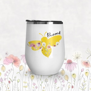May include: White stainless steel wine tumbler with a yellow bee silhouette filled with flowers and the word "Buzzed" in black text.