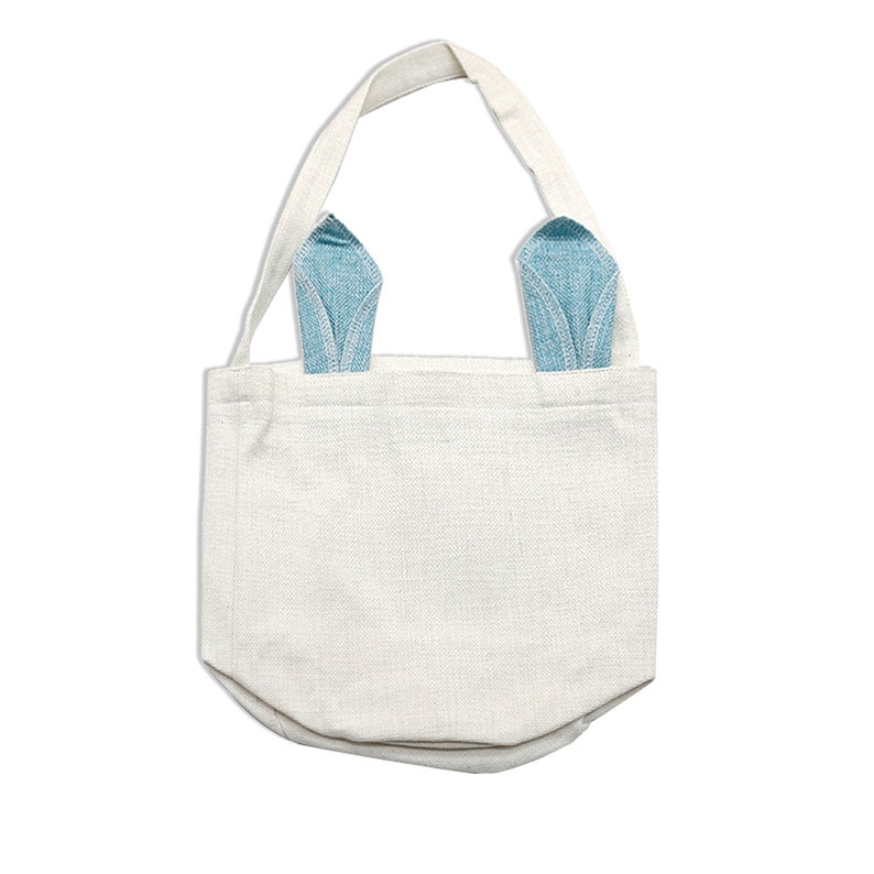 May include: A white canvas tote bag with blue denim bunny ears. The bag has a simple design and is ideal for carrying small items.