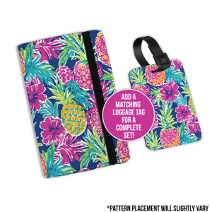 May include: A passport holder and luggage tag set featuring a tropical pineapple and floral design in yellow, pink, green, and blue. The passport holder has a black elastic band. The luggage tag has a black strap. Text on the image reads: "ADD A MATCHING LUGGAGE TAG FOR A COMPLETE SET!"