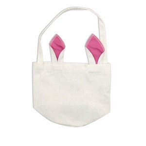 Puede incluir: Una bolsa de lona blanca con orejas de conejo rosas. La bolsa tiene un solo asa y est&aacute; hecha de una tela natural.