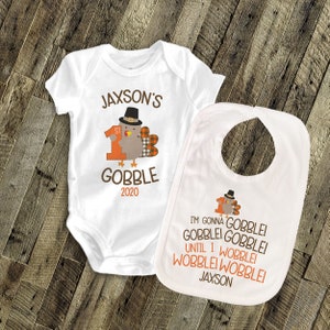 May include: White baby bodysuit and bib with a Thanksgiving turkey design. The bodysuit says "Jaxson's 1st Gobble 2020". The bib says "I'm gonna gobble gobblei gobblei until I wobblei wobblei wobblei Jaxson".