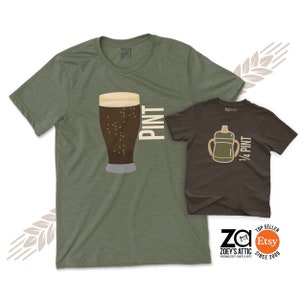 May include: A green t-shirt with a graphic of a pint glass of beer and the word "PINT". A brown t-shirt with a graphic of a sippy cup and the text "1/4 PINT".
