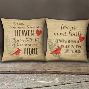 May include: Two decorative throw pillows with a burlap-like texture. The left pillow features a red cardinal and the text "Because someone we love is in HEAVEN there's a little bit of heaven in our HOME". The right pillow features a red cardinal and the text "Forever in our hearts GRANDMA SCHUBERT MARCH. 22, 1930- JAN. 19, 2010".