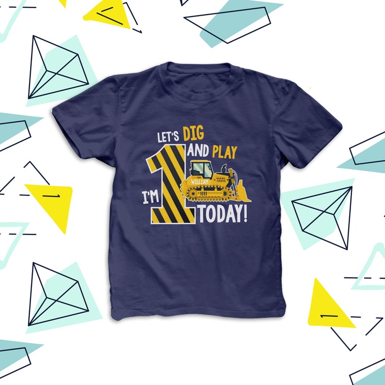 May include: Navy blue t-shirt with a construction theme. The shirt displays the text "Let's Dig and Play, I'm 1 Today!" alongside a yellow and black striped number 1 and a yellow bulldozer graphic. The name "William" is on the bulldozer.