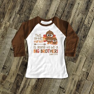 K&ouml;nnte beinhalten: Ein wei&szlig;es Langarmshirt mit braunen &Auml;rmeln. Das Shirt zeigt eine Truthahn-Grafik mit dem Text "This little turkey is going to be a BIG BROTHER! June 2021" und dem Namen "Dalton".