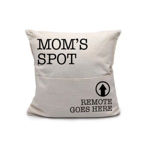 May include: A white pillow with the text "MOM'S SPOT" and a pocket on the bottom with the text "REMOTE GOES HERE" and an arrow pointing upwards.