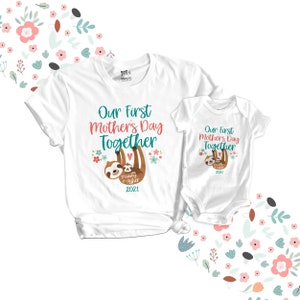 May include: Two white t-shirts with a sloth design. The larger shirt says "Our First Mother's Day Together" with a sloth holding a smaller sloth. The smaller shirt says "Our First Mother's Day Together" with a sloth holding a smaller sloth. Both shirts have the year 2021 printed on them.