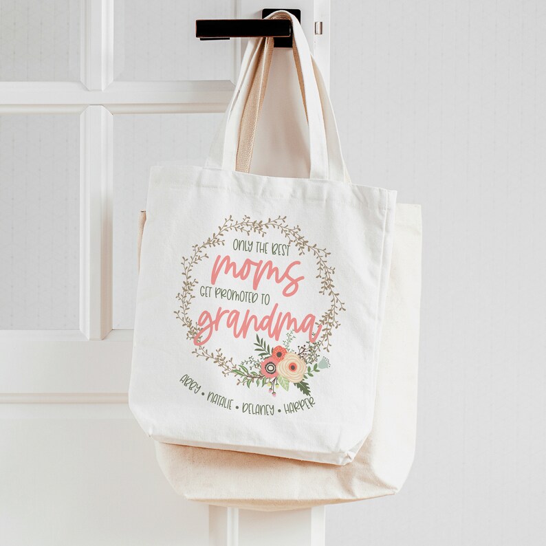 May include: White canvas tote bag with the text "Only the best moms get promoted to grandma" in a floral wreath. The names Abby, Natalie, Delaney, and Harper are listed below the wreath.