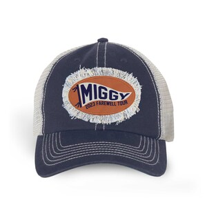 May include: A navy blue and white trucker hat with a distressed oval patch that says "Miggy 2023 Farewell Tour" in navy blue lettering on an orange background.