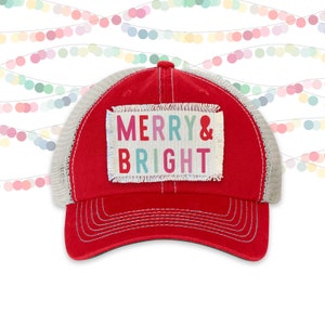 May include: Red and gray trucker hat with a white patch that says "Merry & Bright" in colorful letters.
