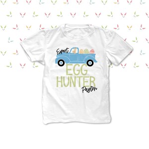 May include: White t-shirt with a light blue truck design carrying Easter eggs. The text reads "Expert Egg Hunter Payton". The background features a pattern of colourful bunny ears.