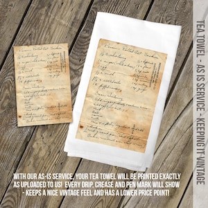 May include: A white tea towel featuring a printed reproduction of a vintage, stained recipe card for Raisin-Rolled Oat Cookies. The print includes handwritten cursive text, visible creases, and aged paper discoloration, replicating the original document.