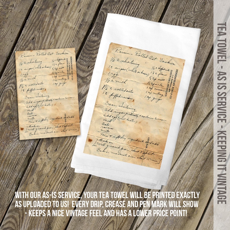 May include: A white tea towel featuring a printed reproduction of a vintage, stained recipe card for Raisin-Rolled Oat Cookies. The print includes handwritten cursive text, visible creases, and aged paper discoloration, replicating the original document.