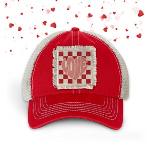 May include: Red and white trucker hat with a checkered patch that says "LOVE" in a heart shape.
