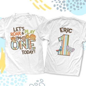 May include: White t-shirts with a jungle theme. One shirt has the text "LET'S ROAR & PLAY I'M ONE TODAY!" with animal graphics. The other shirt has the name "Eric" and the number "1" with animal graphics.