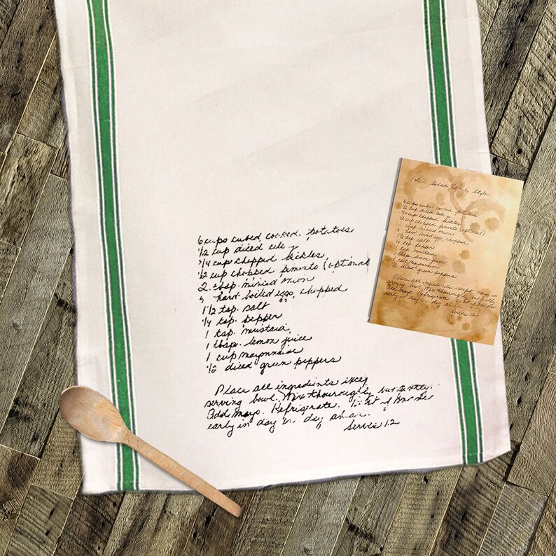 May include: A white tea towel with green stripes and handwritten instructions for a potato salad recipe. The recipe includes ingredients like cooked potatoes, celery, pickles, mayonnaise, mustard, and lemon juice. The text also includes instructions to mix the ingredients thoroughly and refrigerate before serving.