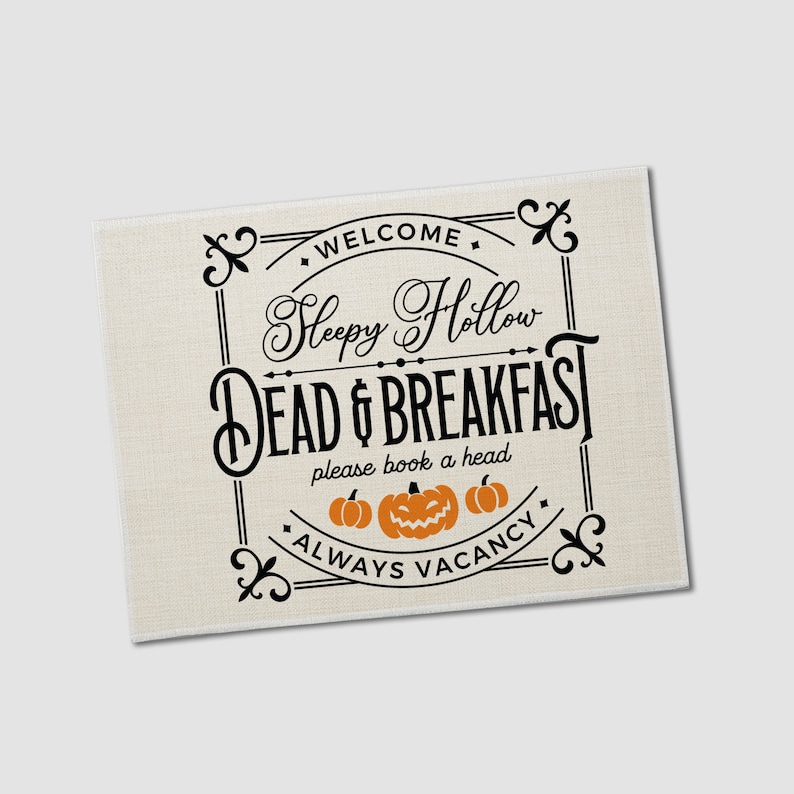 May include: A black and white sign with a vintage design that says "Sleepy Hollow Dead & Breakfast" with three orange pumpkins underneath. The sign says "Welcome" at the top and "Always Vacancy" at the bottom.