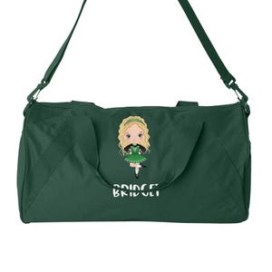May include: Green duffel bag featuring a cartoon illustration of a girl in a green Irish dancing dress. The bag is embroidered with the name "Bridget" in white.
