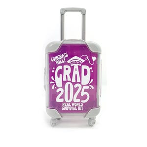 May include: A small pink suitcase with a white handle and wheels. The suitcase has a white sticker that says "Congrats Will! Mizzou Grad 2025 Real World Survival Kit".